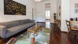 Un salón con sofá, mesa de centro y un bodegón con frutas.