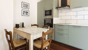 Una cocina compacta con mesa, sillas, microondas, horno y un refrigerador pequeño.