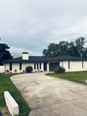 A single-story house with a garage, a driveway, and a lawn.