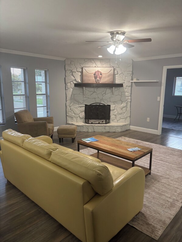 A living room with a stone fireplace, a ceiling fan, a sofa, and a coffee table.