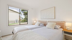 Ein Schlafzimmer mit zwei Betten, einem großen Fenster, einem Wandbild und Nachttischlampen.