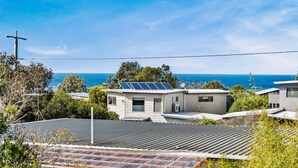 Uma casa moderna com painéis solares, antena parabólica e vista para o oceano.