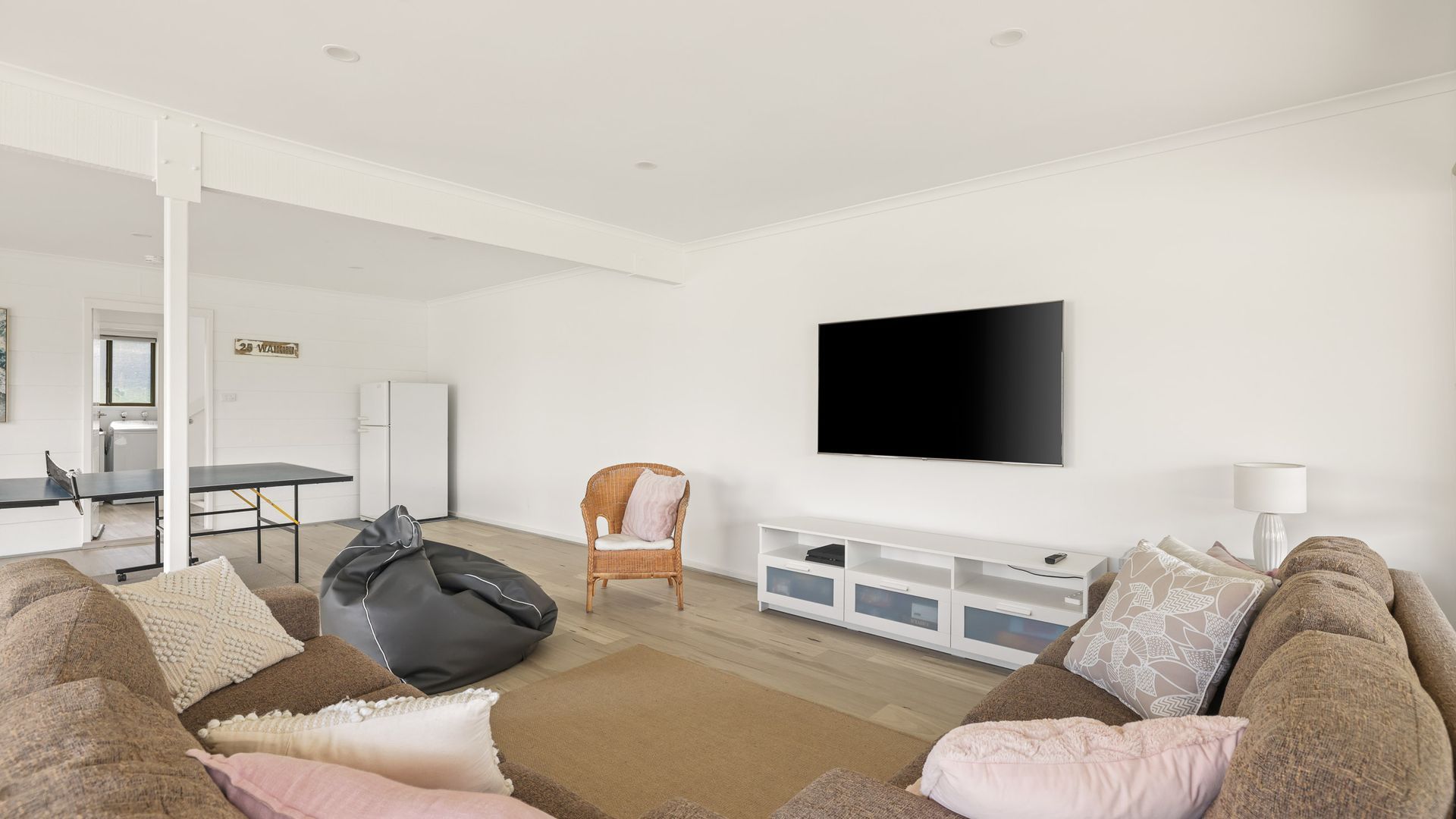 En moderne stue med sofaarrangement, en saccosek, et fladskærms-tv og et spiseområde med bord og stole.