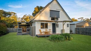 Een gelijkvloers huis met een overdekte patio, een omheinde achtertuin en een klein terras.
