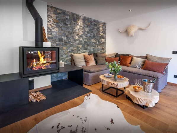 A modern living room with a stone wall, a fireplace, a sofa, and a cow skull decoration.
