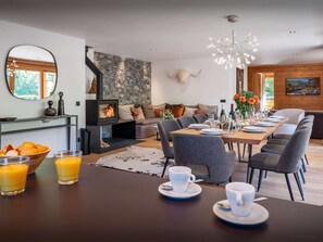 A modern dining area with a stone wall, a fireplace, and a dining table set for a meal.