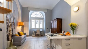 A modern kitchen with a dining area, a large window, and a vase with flowers on the counter. - GuestHost - Consolata Square Elegant Loft x4 (Torino)