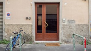 Ein Gebäudeeingang mit einer Holztür, ein Fahrrad, das davor abgestellt ist, und ein Schild mit der Aufschrift 'passo carrabile'.