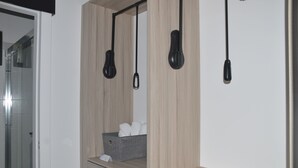 A modern bathroom with a wooden vanity, a towel rack, and a small storage bin.