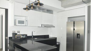 A modern kitchen with a black countertop, stainless steel appliances, and a welcome sign.