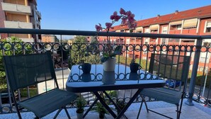 A balcony with a table and chairs, potted plants, and a view of buildings in the background. - Bnbook TommasoGrossi Studio (Rho)