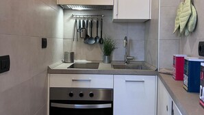 A modern kitchen with white cabinets, stainless steel appliances, and a variety of utensils hanging on a rack. - Bnbook TommasoGrossi Studio (Rho)