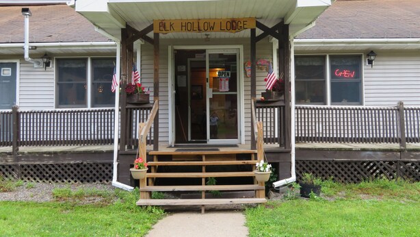 A building with a porch labeled "ELK HOLLOW LODGE" and a sign indicating it's open. - located next to gamelands next to nature (Benton)