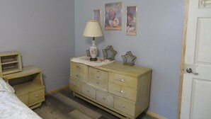 A bedroom with a bed, a dresser, a nightstand, and a door. - located next to gamelands next to nature (Benton)
