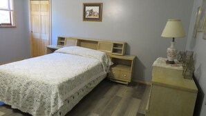 A bedroom with a bed, a nightstand, a lamp, and a picture on the wall. - located next to gamelands next to nature (Benton)