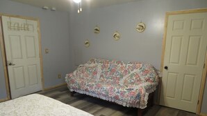 A bedroom with a floral-patterned sofa, a bed with a white floral bedspread, and three wall-mounted fish-themed decorations. - located next to gamelands next to nature (Benton)