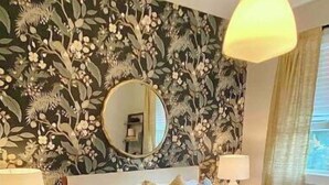 A bedroom with a large bed, a mirror, two bedside tables, and a leopard print rug. - Birdie's: A New 2b in Downtown Hillsboro (Hillsboro)
