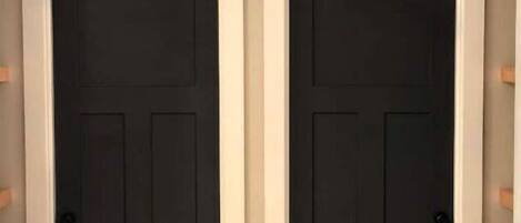 A hallway with two black doors, a white trim, and a hanging pendant light.