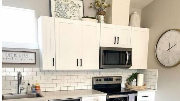 A compact kitchen with white cabinets, a microwave, a stove, and a dining area with a wooden table and two chairs. - Birdie's: A New 2b in Downtown Hillsboro (Hillsboro)