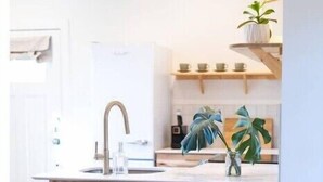A modern kitchen with a central island, two black stools, a sink, and pendant lighting. - The Isabella Lofthouse on Colorado-Walk to Main

 (Buena Vista)