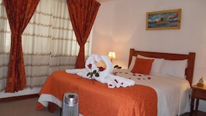 A hotel room with a bed, a nightstand, a lamp, and a painting on the wall. - HOTEL PUNO TERRA (Puno)