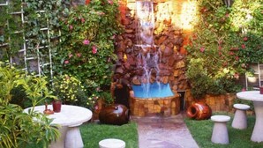 A garden with a waterfall, stone wall, and outdoor seating area. - HOTEL PUNO TERRA (Puno)