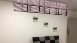 A room with a sofa, a bed, and a door. There are three paintings on the wall.