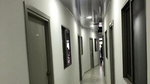 A long, narrow hallway with doors on both sides, tiled floor, and recessed lighting.