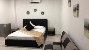 A bedroom with a bed, a sofa, a small table, and wall decorations.