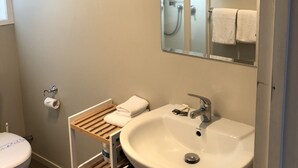 A bathroom with a toilet, a sink, a mirror, and a towel rack. - In the Centre of Ohakune township (Ohakune)