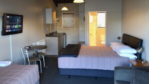 A hotel room with a bed, a desk with a chair, a television, and a bathroom visible through an open door. - In the Centre of Ohakune township (Ohakune)