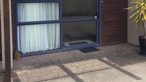 A garage door with a sliding glass window, a potted plant, and a brick driveway. - In the Centre of Ohakune township (Ohakune)