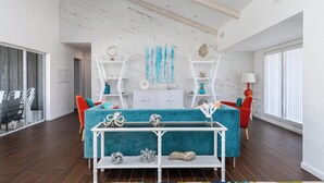 Una sala moderna con un sofá color turquesa, estantes blancos y techo de madera.