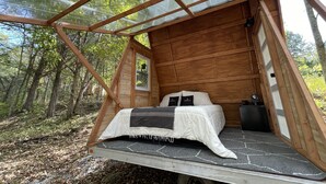 A cozy wooden cabin with a bed, a window, and a small table. - Lakefront Transforming Micro Cottage on Cherokee Lake  (Mooresburg)