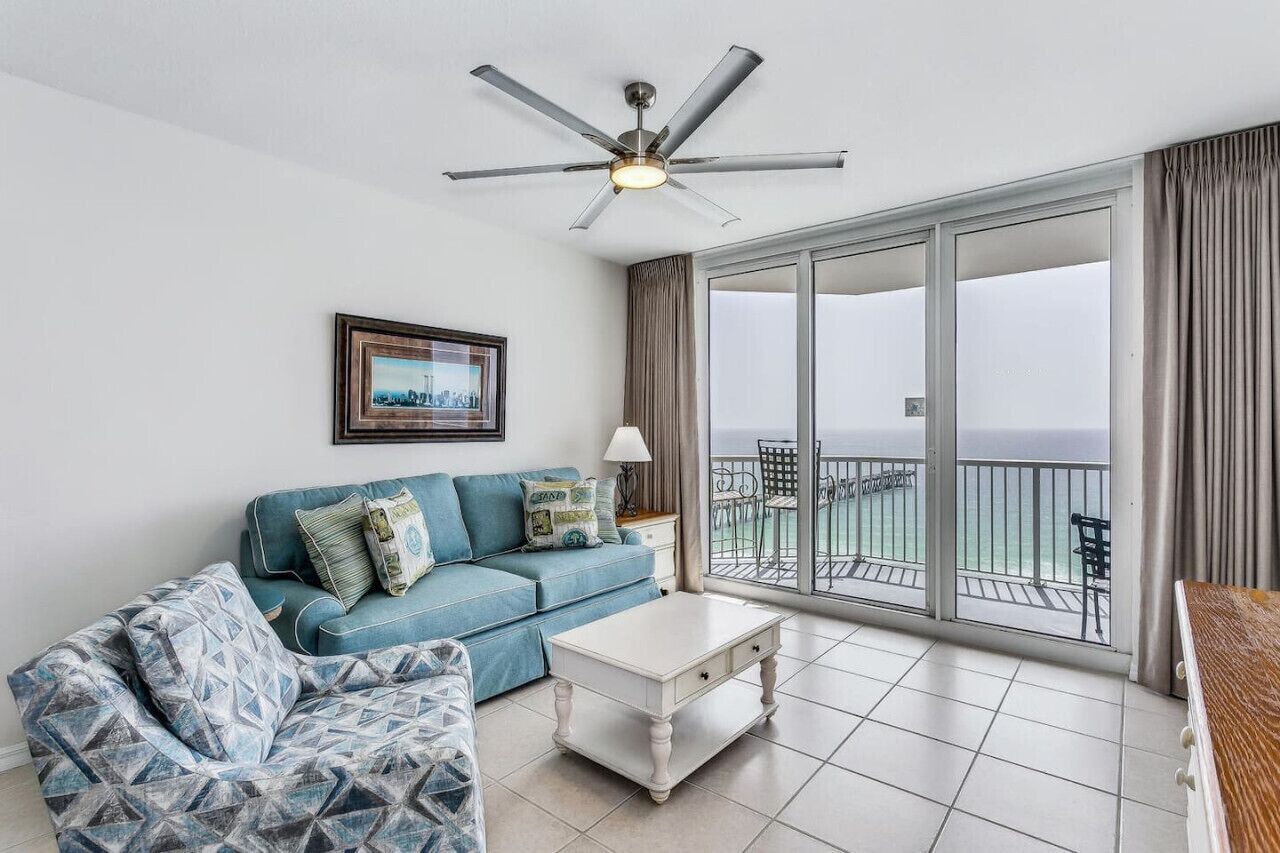 A modern living room with a blue sofa, a white coffee table, and a ceiling fan.