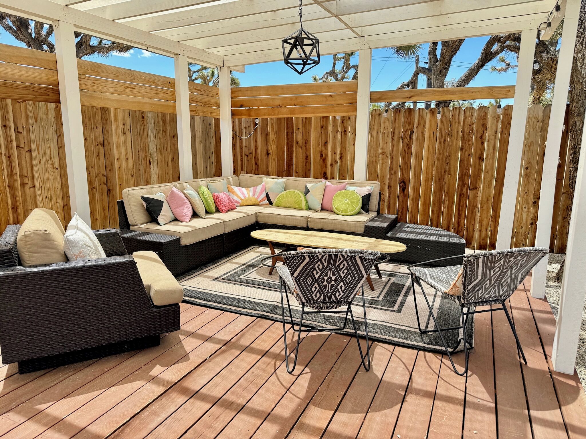Eine überdachte Terrasse mit einer Eckcouch, einem runden Tisch und zwei Stühlen.
