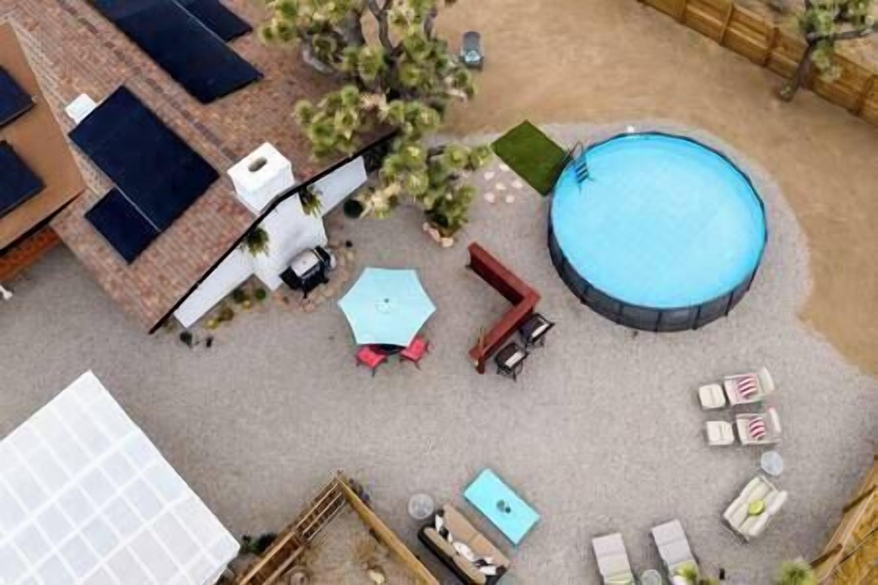 An aerial view of a backyard with a swimming pool, patio furniture, and a small shed.
