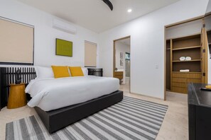 Ein modernes Schlafzimmer mit einem großen Bett, einem Nachttisch, einem Kleiderschrank und einem durchgegangene Tür erkennbaren Badezimmer.