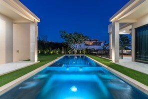 Ein Swimmingpool mit Blick auf ein modernes Haus im Hintergrund.