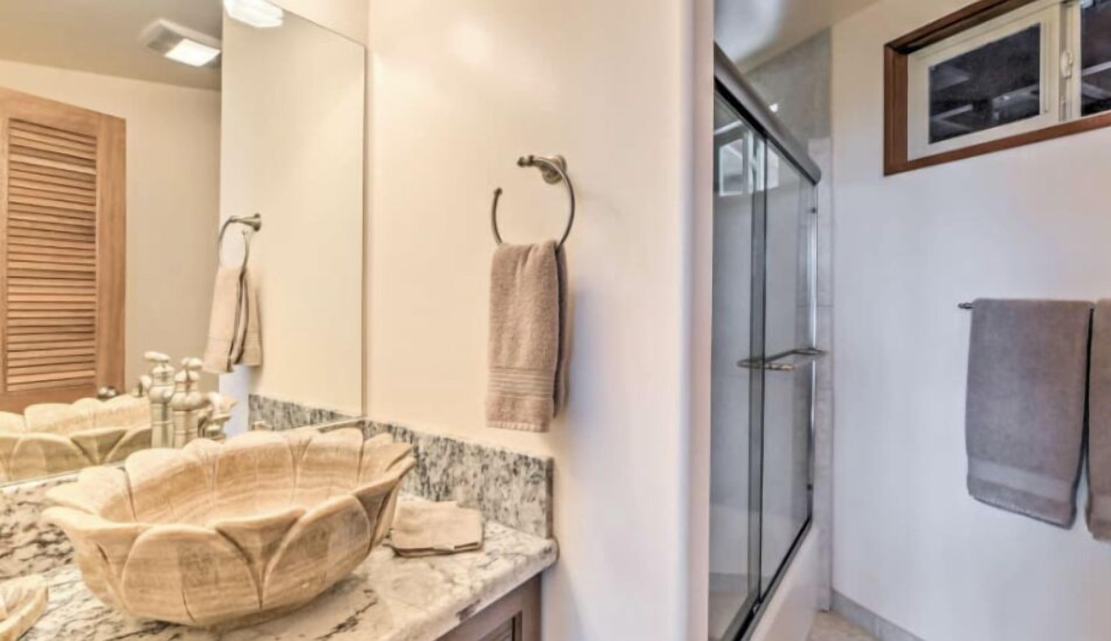 A bathroom with a marble sink, a large mirror, and a glass shower enclosure.