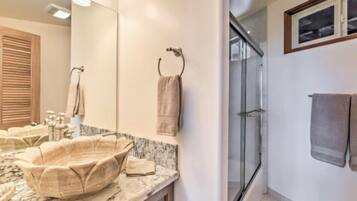 A bathroom with a marble sink, a large mirror, and a glass shower enclosure.