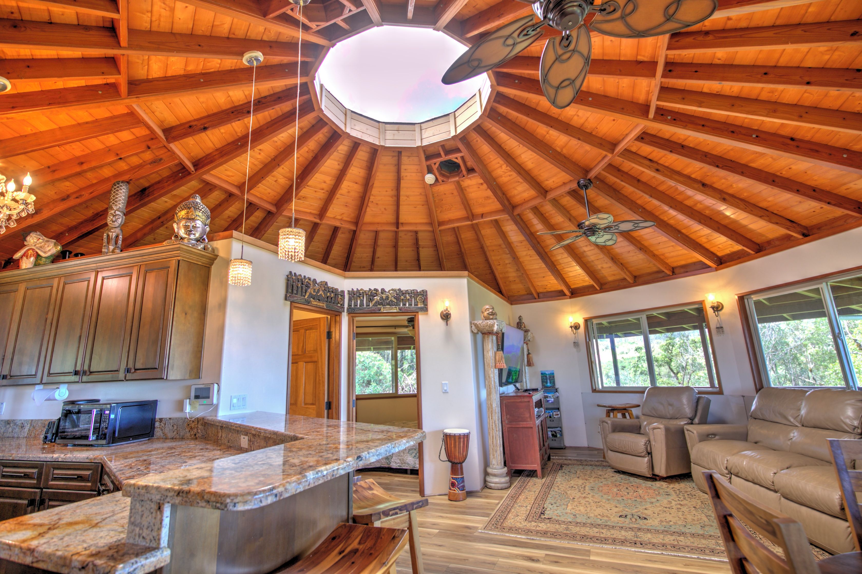 A spacious living area with a high wooden ceiling, a large window, and a seating area with a sofa and chairs.