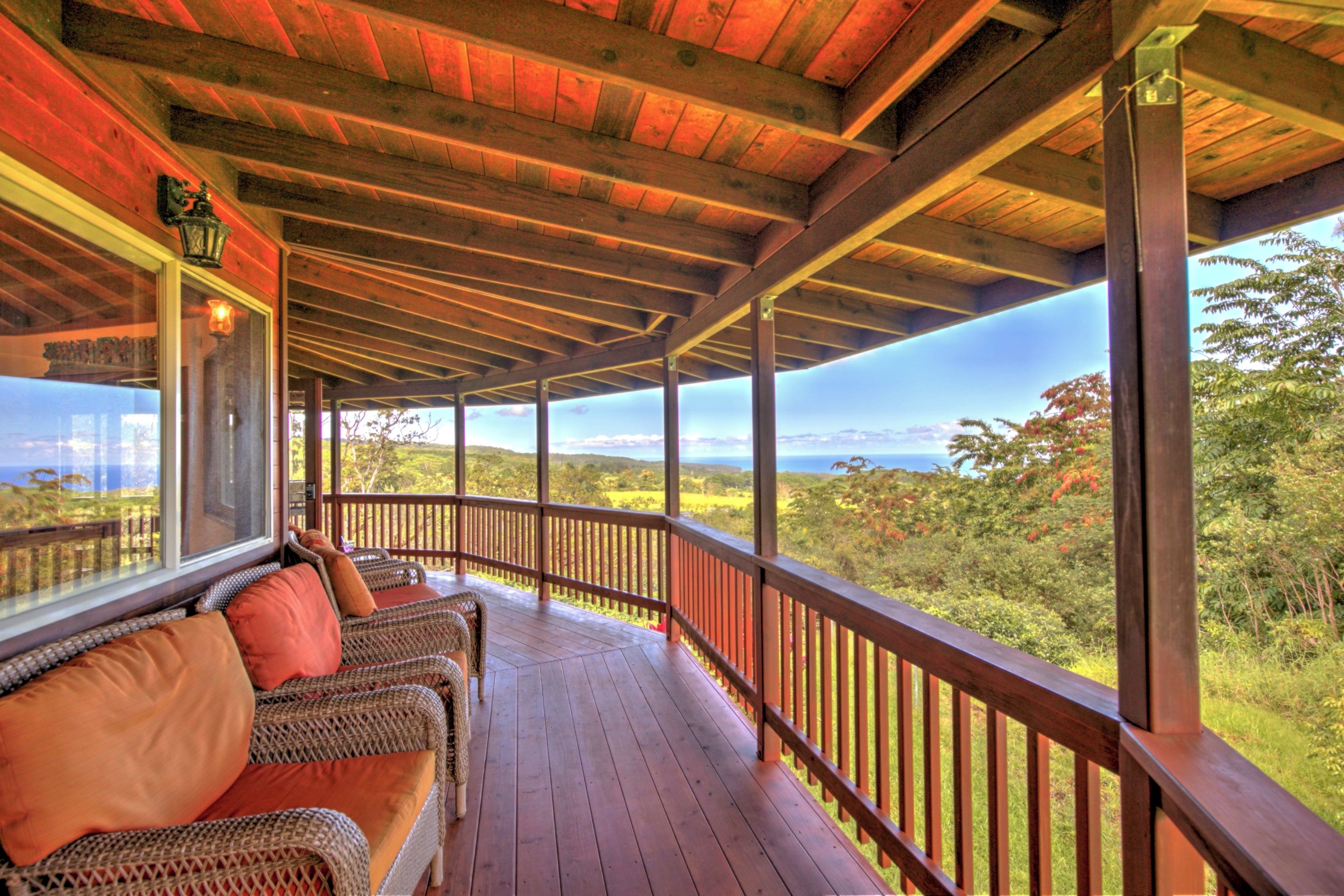 A covered porch with wicker furniture and a view of the landscape.