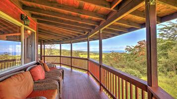 A covered porch with wicker furniture and a view of the landscape.