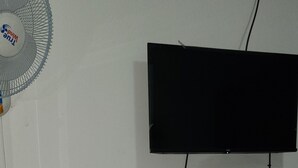 A wall-mounted television with a cable running to a power outlet. - Hospedaje Casa de Luna (Tegucigalpa)