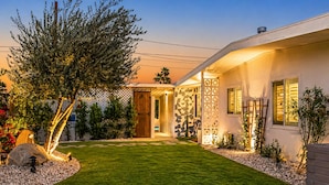 Una casa moderna con un prato curato, una porta in legno e un muro in pietra.