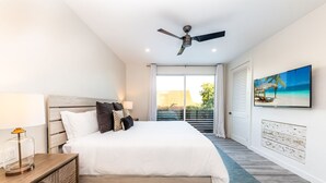 A bedroom with a large bed, a ceiling fan, a TV, and a view of the outdoors. - 30% Off September! Walk To Beach/Pool-CV41-2 (Leeward Settlement)