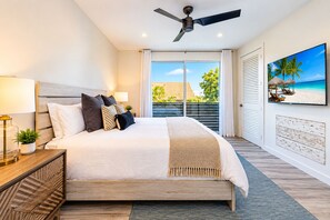 Une chambre moderne avec un grand lit, un ventilateur de plafond, une télévision et une vue sur l’extérieur.