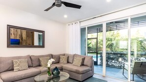 A modern living room with a sectional sofa, a glass coffee table, and a large sliding glass door leading to a balcony. - 25% Off Sept 17-20!  Walk To Beach/Pool* -CV41-4 (Leeward Settlement)