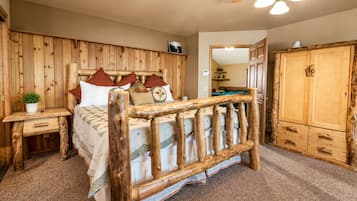 Ein Zimmer mit einem hölzernen Bett, einem Nachttisch, einem Kleiderschrank und einem Deckenventilator.